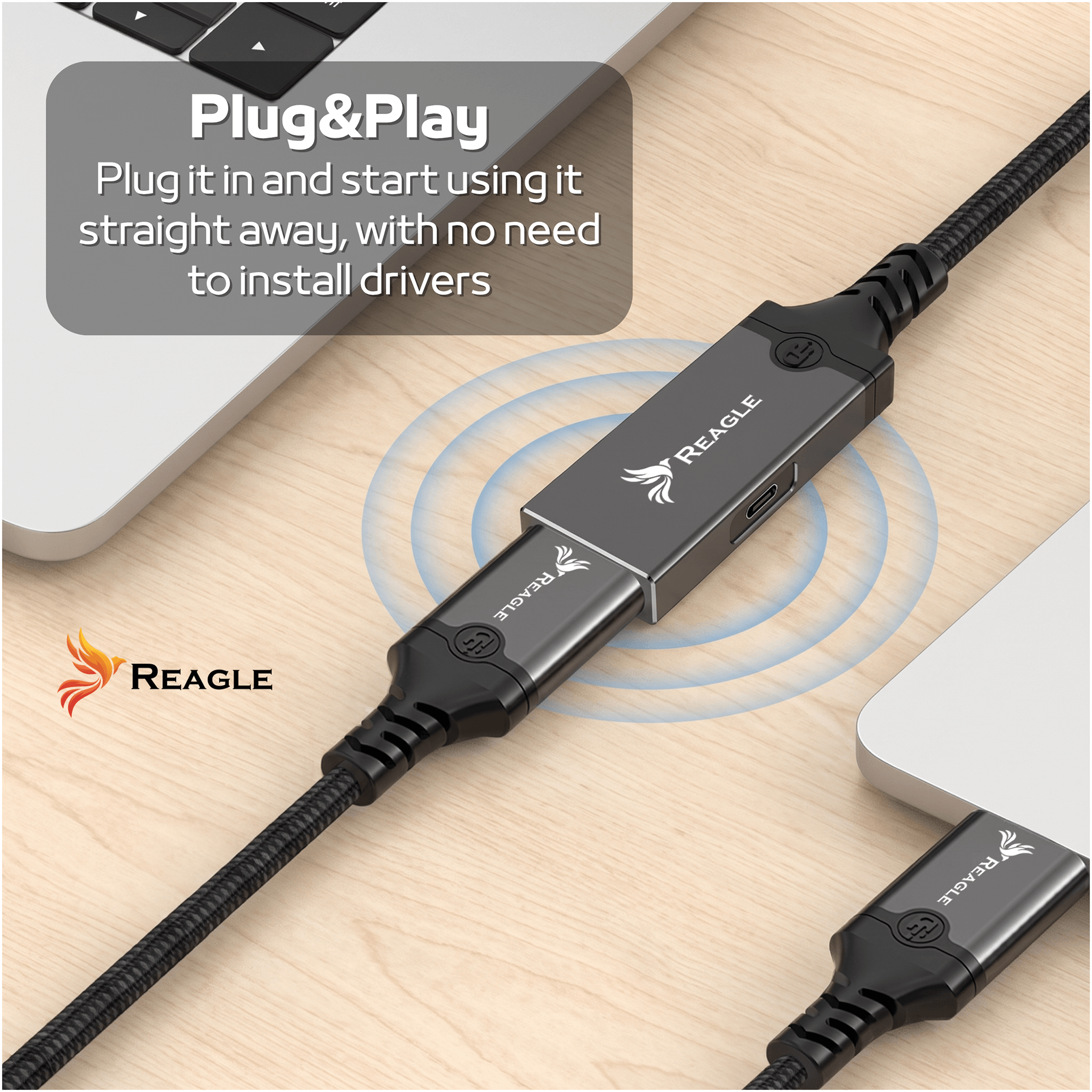 Na drewnianym blacie znajduje się aktywny kabel USB z logo REAGLE, podłączony do dwóch urządzeń. Na obrazie widoczny jest tekst: \'Plug&Play Plug it in and start using it straight away, with no need to install drivers\'.