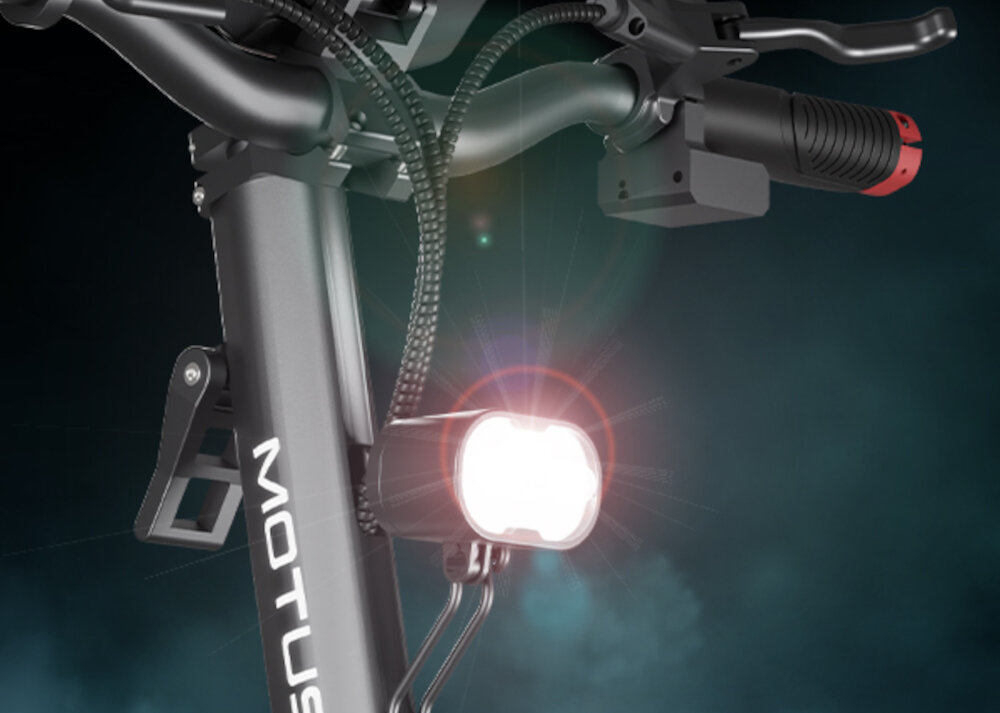 Hulajnoga elektryczna MOTUS Pro 10 Daytona 65km 2x1000W Amortyzacja 10 cali Czarny zbliżenie na przednią lampę lampa świeci duże lampy z przodu z tyłu bezpieczeństwo bardzo dobrze widoczny na drodze kierunkowskazy