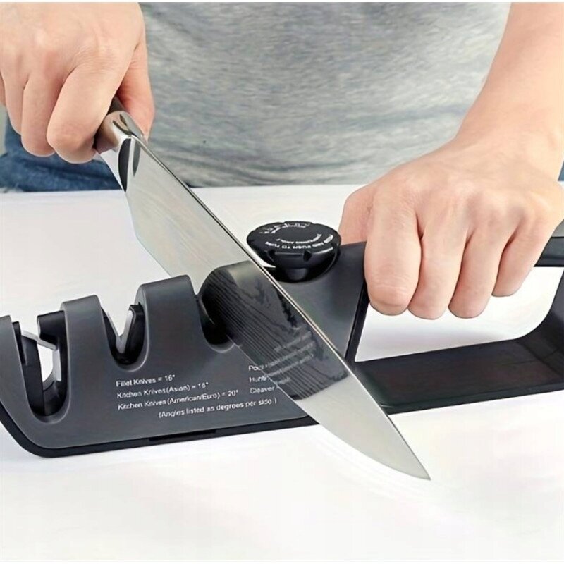 Osoba używa trójfazowej ostrzałki do noży, przesuwając nóż przez szczeliny urządzenia. Na ostrzałce widoczny jest tekst: \'Fillet Knives = 16°, Kitchen Knives (Asian) = 16°, Kitchen Knives (American/Euro) = 20°\'.