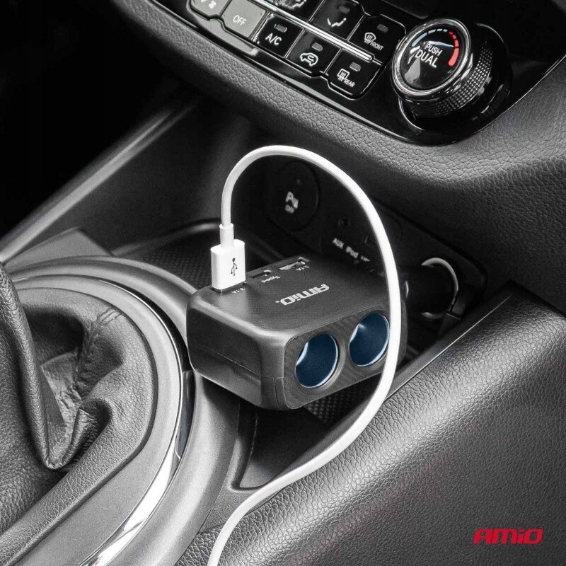 Na zdjęciu widać rozdzielacz gniazda zapalniczki z dwoma portami USB i jednym USB-C, podłączony w samochodzie. Na urządzeniu widoczne jest logo \'AMiO\'.