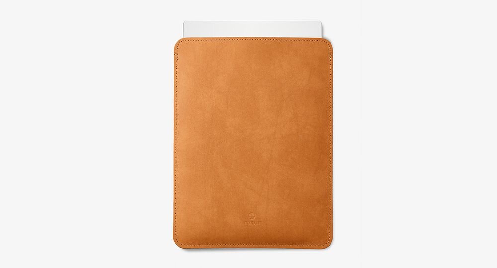 Jasnobrązowe etui na laptopa z widocznym logo producenta na środku. Wewnątrz etui znajduje się biały element, prawdopodobnie część laptopa.