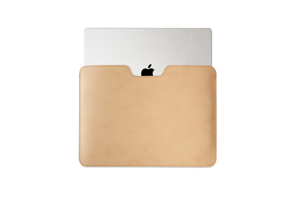 Beżowe etui na laptopa z widocznym logo producenta, częściowo zasłaniające srebrny laptop z czarnym logo jabłka.