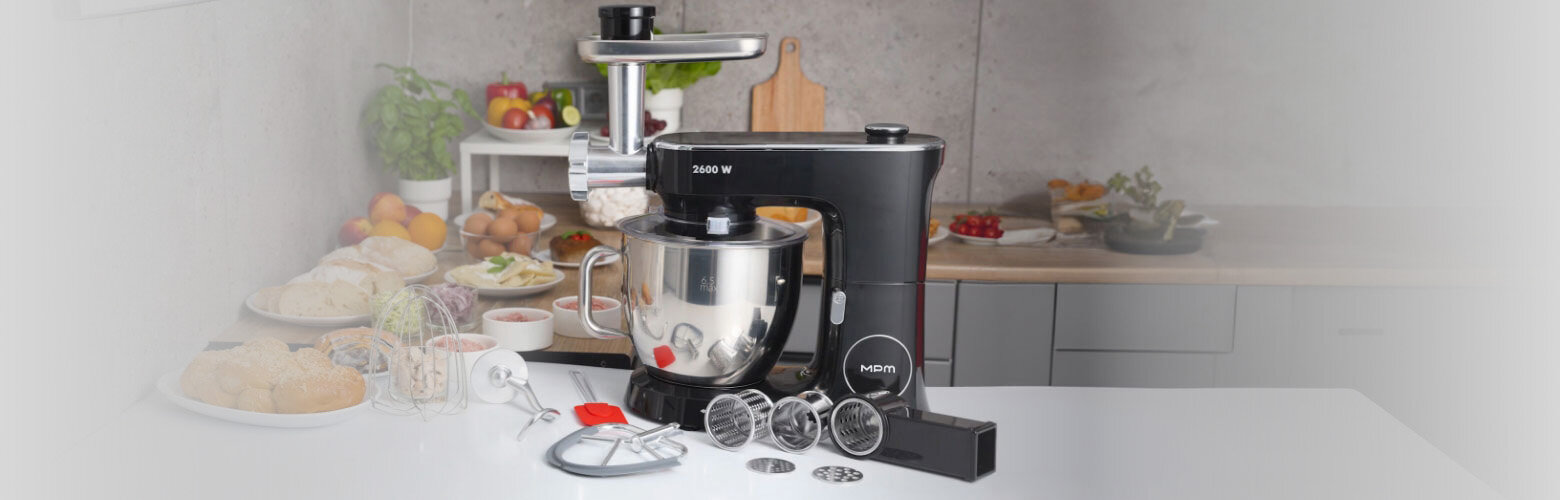 Robot planetarny 3W1 MRK-26 na kuchennym blacie. Wokół niego akcesoria i różne potrawy.