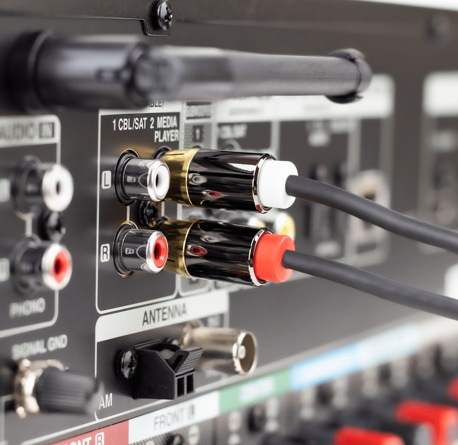 Zbliżenie na tylny panel urządzenia audio z podłączonymi kablami RCA. Widoczne są gniazda oznaczone jako \'L\' i \'R\' oraz napisy \'ANTENNA\' i \'AM\'.
