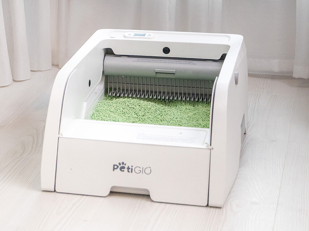 PetiGIO PETI-261 neutralizacja zapachów Green Tea Biała, nowoczesna kuweta automatyczna PetiGiò z widocznym mechanizmem grabiącym. Wewnątrz urządzenia znajduje się warstwa zielonego żwirku tofu o zapachu zielonej herbaty.