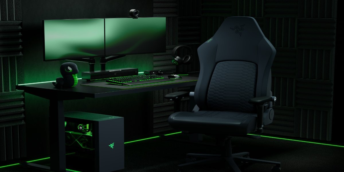 Fotel gamingowy Razer Iskur V2 Newgen przy stacji gamingowej na tle pokoju obłożonego pianką akustyczną.