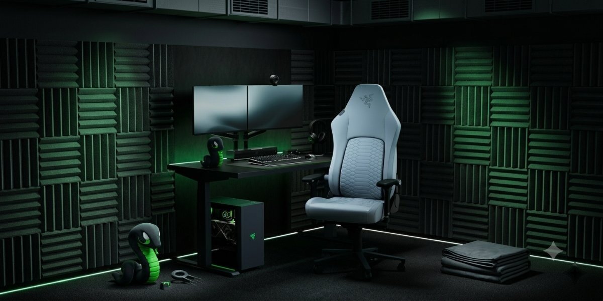 Fotel gamingowy Razer Iskur V2 Newgen przy stacji gamingowej na tle pokoju obłożonego pianką akustyczną.