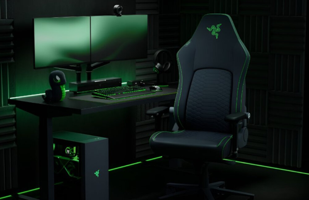 Fotel gamingowy Razer Iskur V2 Newgen przy stacji gamingowej na tle pokoju obłożonego pianką akustyczną.