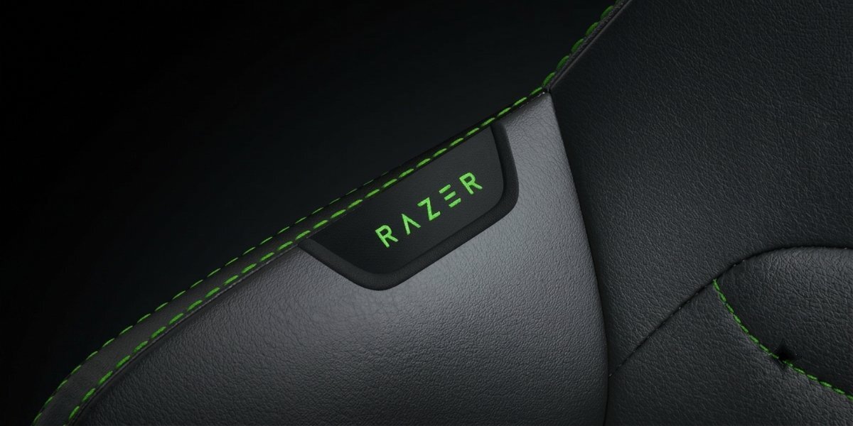 Przybliżenie na element krzesła Razer Iskur V2 Newgen, widoczne jest naszyte logo 'RAZER'.