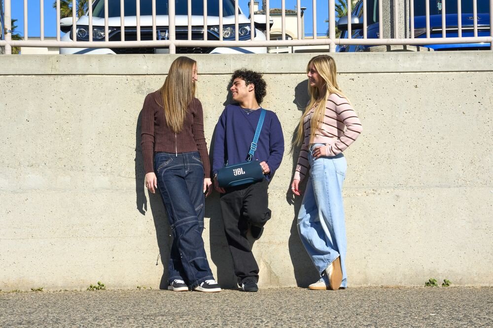 Głośnik mobilny JBL Xtreme 5 Smart EQ automatyczna regulacja dźwięku podcast muzyka, osoba z przewieszonym głośnikiem mobilnym przez ramię