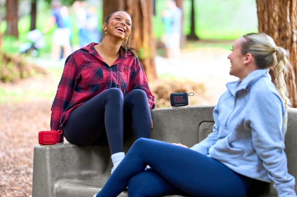 JBL Go 5 USB-C dźwięk bezstratny ładowanie przewodowe wysoka jakość audio, osoby siedzące na ławce obok dwóch głośników mobilnych