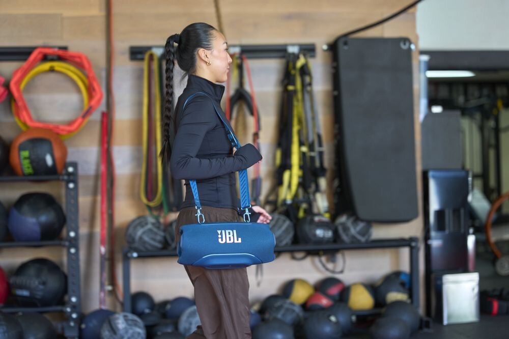 Głośnik mobilny JBL Xtreme 5 podświetlenie LED rytm muzyki status baterii Bluetooth, osoba z przewieszonym głośnikiem mobilnym przez ramię