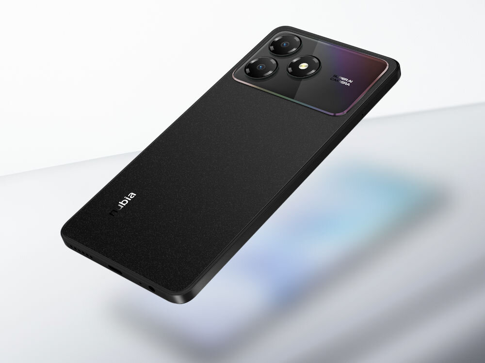 Smartfon ZTE Blade A36 4/64GB 6.75 90Hz Czarny Telefon ZTE/nubia w kolorze czarnym, widok od tyłu, unosi się nad jasnym tłem. Tył telefonu ma teksturę. Moduł potrójnego aparatu mieni się tęczowymi refleksami.