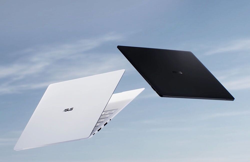 Dwa laptopy w kolorach białym i czarnym unoszą się na tle nieba. Na obudowach widoczne jest logo ASUS.