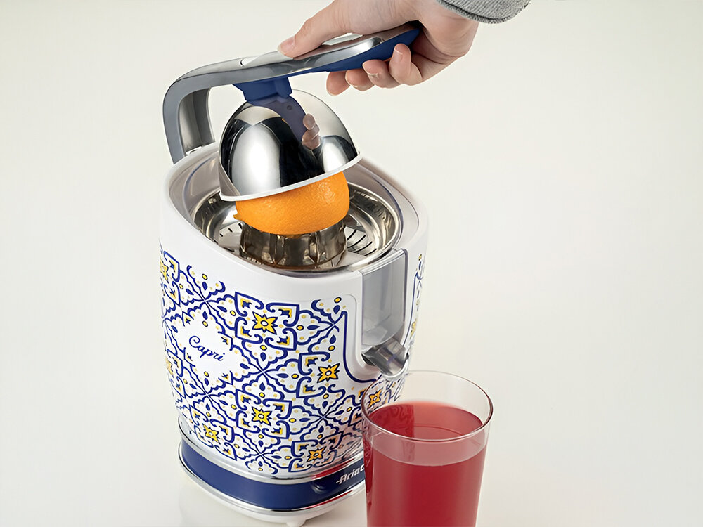 Wyciskarka do cytrusów ARIETE Capri 413 jasne tło wyciskarka biało niebieska kolorystyka obudowy żółte elementy metalowe elementy osoba wyciska sok z grejpfruta czerwony sok w szklance Ergonomiczna dźwignia maksymalny komfort użytkowania efektywne wyciskanie soku dwa stożki o różnych rozmiarach mniejszy do cytryn i limonek większy pomarańcze grejpfruty wszechstronna świeże i aromatyczne soki 