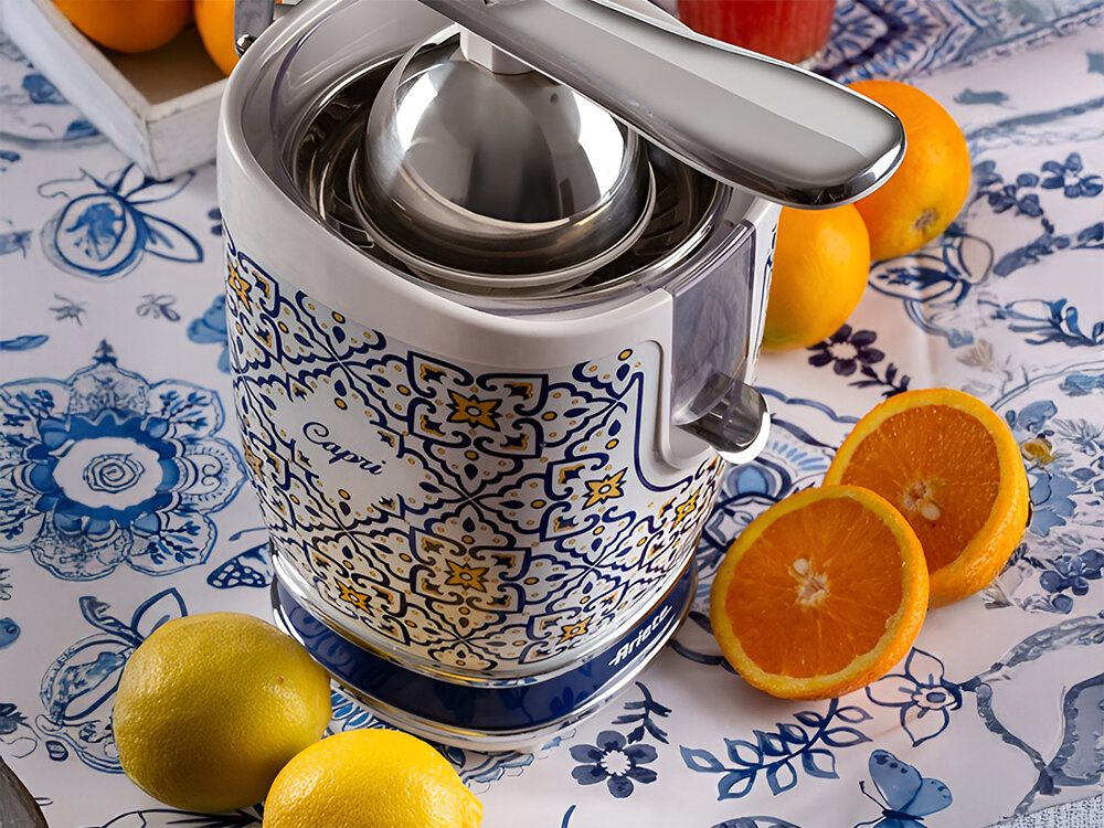 Wyciskarka do cytrusów ARIETE Capri 413 biało niebieska kolorystyka z żółtymi elementami metalowe elementy obok urządzenia leżą pomarańcze i cytryny świeżość prosto z natury codzienne zdrowe napoje rześkie koktajle cytrynowe zdrowe wersje drinków oaza zdrowia i smaku pełno witamin wyjątkowy aromat 