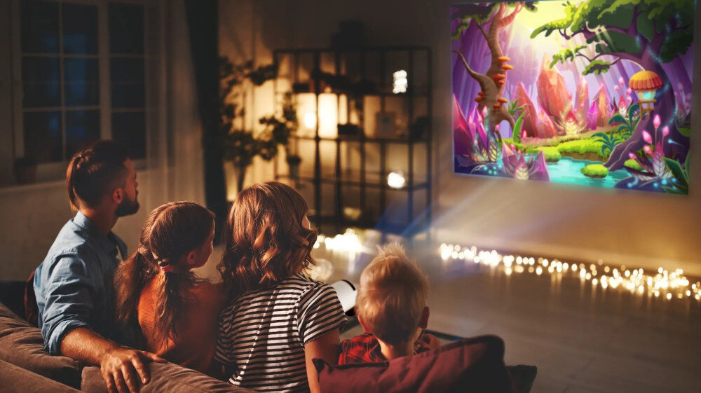 Projektor KIANO Relax funkcje smart Netflix YouTube screen mirroring bezprzewodowe przesyłanie obrazu, rodzina oglądające kreskówkę w salonie