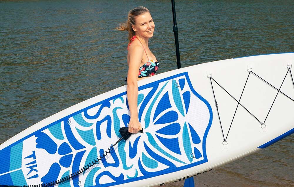 Deska SUP FUNWATER SUPFW05B Niebiesko-biały, uniwersalna, deska, rekreacja, jezioro, Kobieta ćwiczy na desce SUP na spokojnej wodzie.