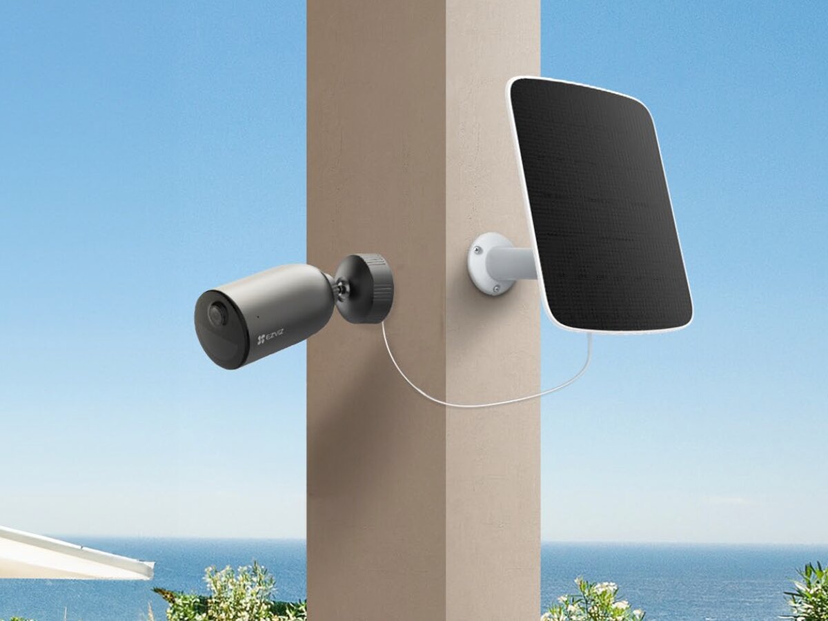 Kamera EZVIZ EB3 Zewnętrzna, 4G LTE + Panel solarny, transmisja, LTE, powiadomienia, kontrola, Kamera i panel słoneczny na jasnym słupku, jasne niebo i zieleń w tle