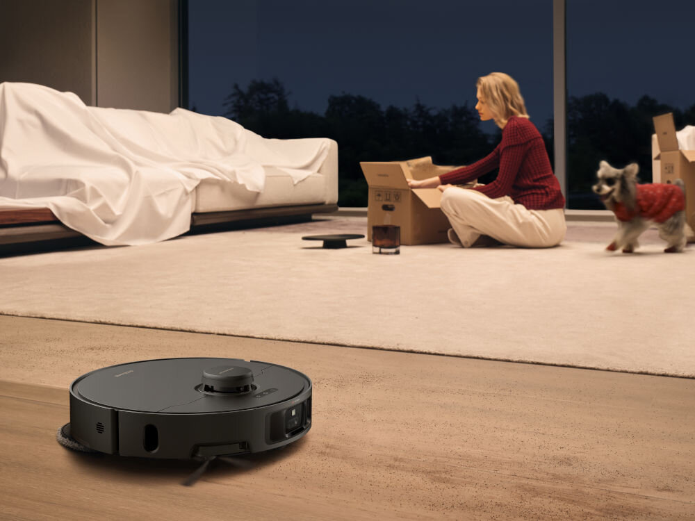 Robot sprzątający DREAME L40S Pro Ultra Czarny robot sprzątający podłogę w tle osoba wypakowująca karton czyszczenie po przeprowadzce płukanie gorącą wodą higieniczne sprzątanie