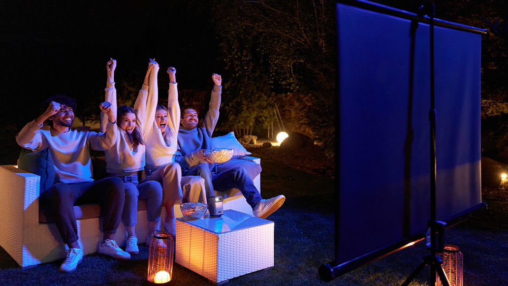 Projektor OVERMAX Multipic 8.1 HD - Mobilna rozrywka, ludzie siedzący na kanapie, oglądający obraz wyświetlany z projektora na ekranie projekcyjnym