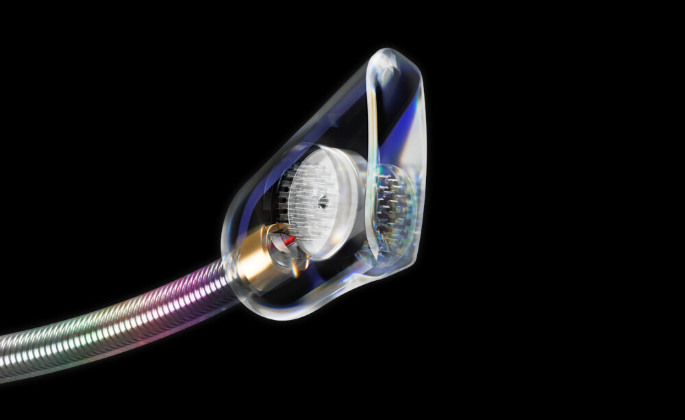 Obraz przedstawia przezroczysty element z metalicznym, spiralnym przewodem, który ma kolorowe refleksy. Wewnątrz widoczny jest okrągły, srebrzysty komponent.