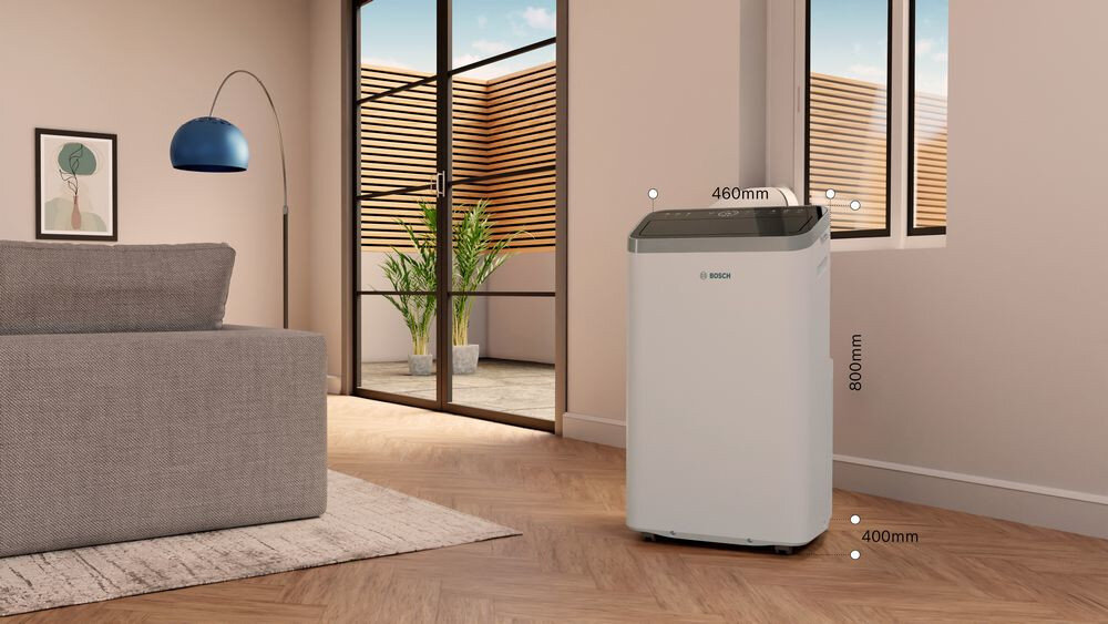 W salonie znajduje się klimatyzator marki BOSCH z widocznymi wymiarami: 460mm szerokości, 800mm wysokości i 400mm głębokości. W tle widać sofę, lampę i roślinę przy dużym oknie.