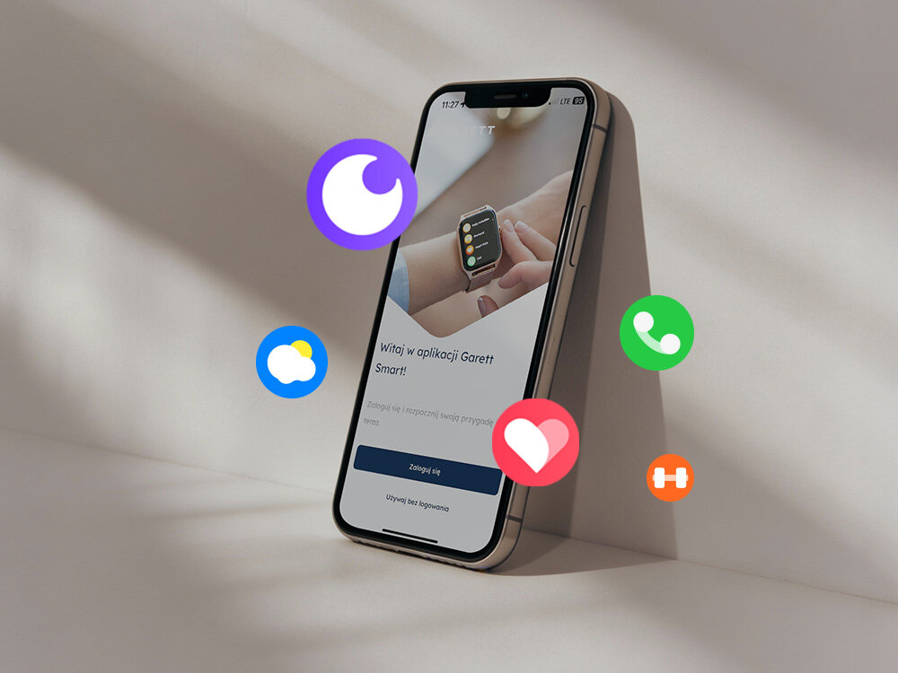 Na obrazie widoczny jest smartfon z aplikacją \'Witaj w aplikacji Garett Smart\', a wokół niego unoszą się kolorowe ikony symbolizujące różne funkcje. Na ekranie telefonu widoczny jest przycisk \'Zaloguj się\'.