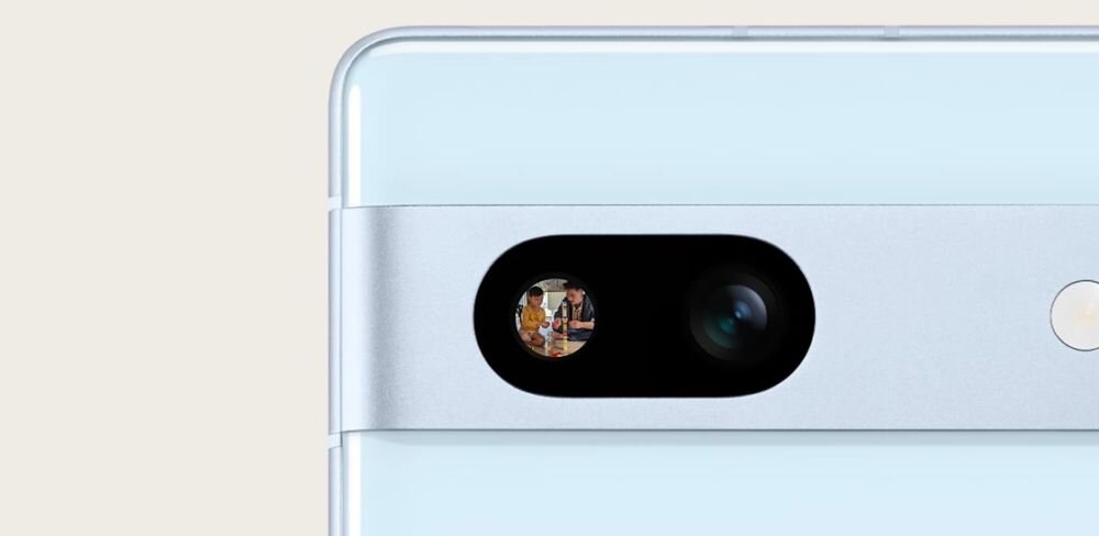 Zbliżenie na tylną część smartfona z widocznym podwójnym aparatem fotograficznym i błyszczącym elementem obok. Obudowa jest w jasnym kolorze z metalicznym wykończeniem wokół aparatu.