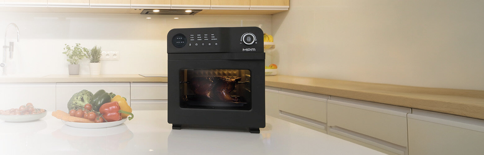 Frytkownica MFR-15 na kuchennym blacie, obok miska z warzywami, w tle meble kuchenne.