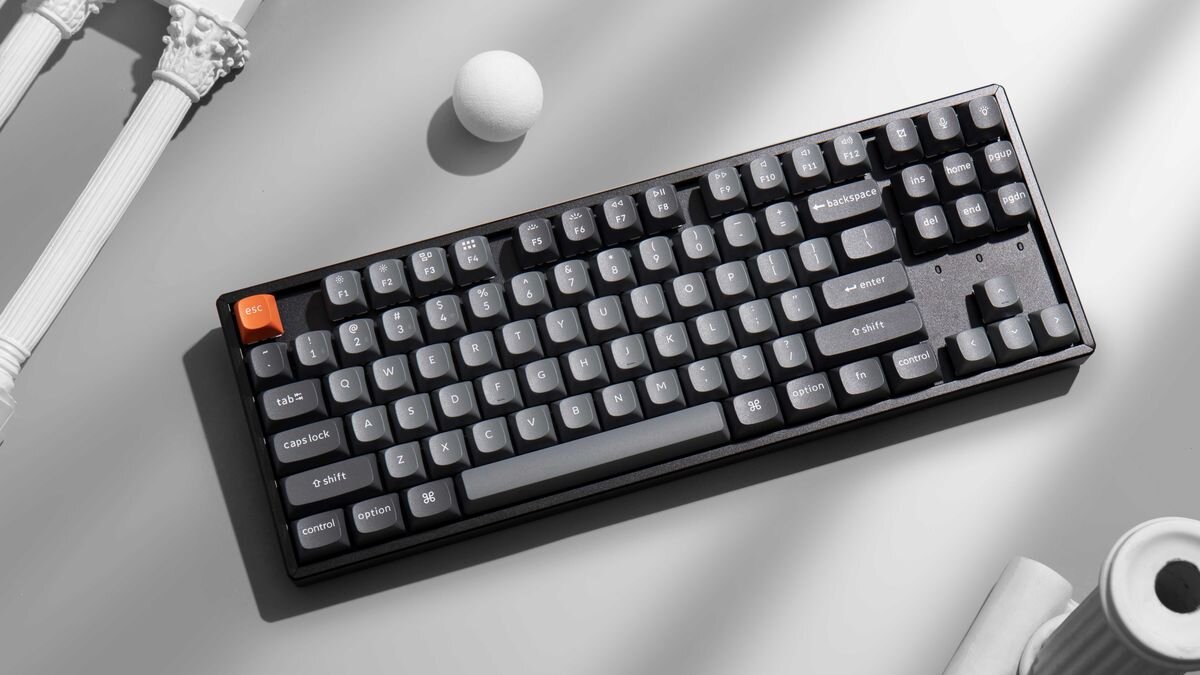 Keychron K8 Max Keychron K8 Max TKL 80% bez bloku numerycznego 87 klawiszy 354,21 × 124,18 × 43,09 mm 1158 g klawiatura full-size - Klawiatura zaprezentowana w widoku z góry w kompozycji z elementami dekoracyjnymi imitującymi kolumny.