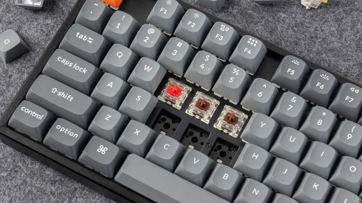 Keychron K8 Max mechaniczne przełączniki Keychron Super Wersja hot-swap bez użycia lutownicy przełącznikami mechanicznymi w standardzie MX (Cherry MX) 3-pinowymi 5-pinowymi - Zbliżenie na klawisze klawiatury, z których część została zdemontowana, odsłaniając przełączniki mechaniczne oraz puste gniazda.