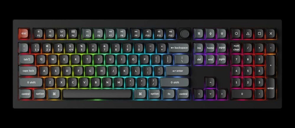 Klawiatura mechaniczna z podświetleniem RGB, posiada pełny układ klawiszy z dodatkowym pokrętłem w górnej części. Klawisze mają różne kolory podświetlenia, a na niektórych widoczne są symbole i napisy, takie jak \'esc\', \'backspace\', \'enter\'.