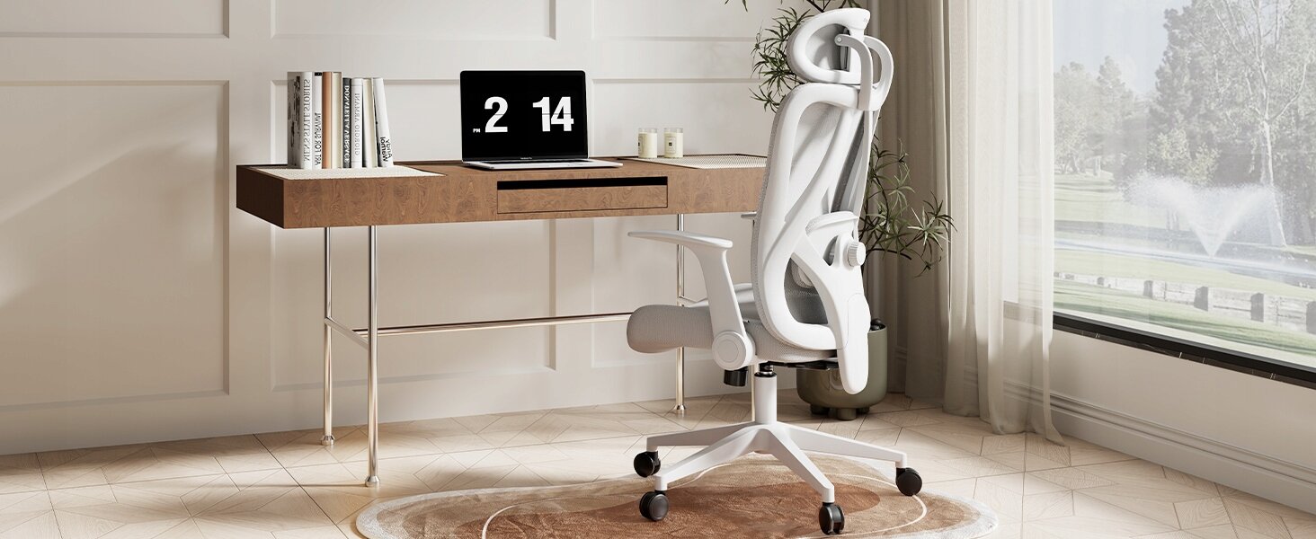 Na obrazie znajduje się biurko z laptopem, na którym widoczny jest tekst \'.2 14\'. Obok biurka stoi ergonomiczne krzesło biurowe z białą ramą i szarym materiałowym obiciem.