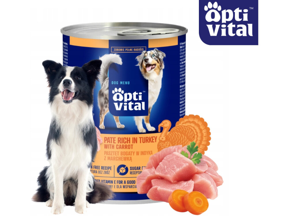 Na obrazie widoczna jest puszka karmy dla psa marki opti vital z wizerunkiem psa oraz napisami \'PATE RICH IN TURKEY WITH CARROT\' i \'PASZTET BOGATY W INDYKA Z MARCHEWKĄ\'. Obok puszki znajduje się pies oraz kawałki mięsa i marchewki.