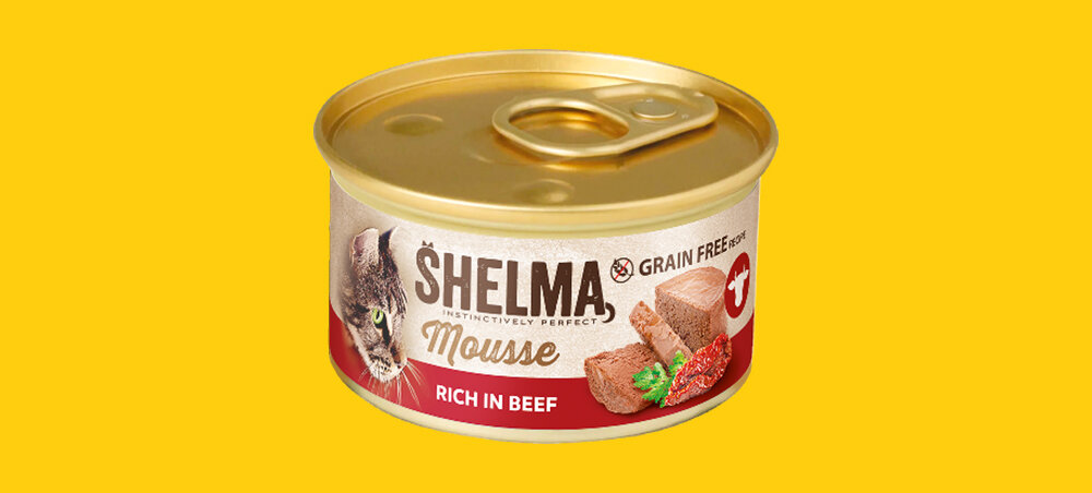 Puszka karmy dla kota marki SHELMA z napisem \'Mousse RICH IN BEEF\' oraz grafiką przedstawiającą kawałki mięsa i kota. Tło jest żółte, a na etykiecie widnieje napis \'GRAIN FREE\'.
