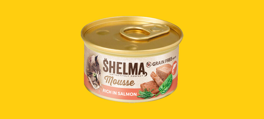 Puszka karmy dla kota SHELMA Mousse z łososiem, na której widnieje napis \'RICH IN SALMON\' oraz ilustracja kawałków mięsa i ziół. Tło jest żółte.