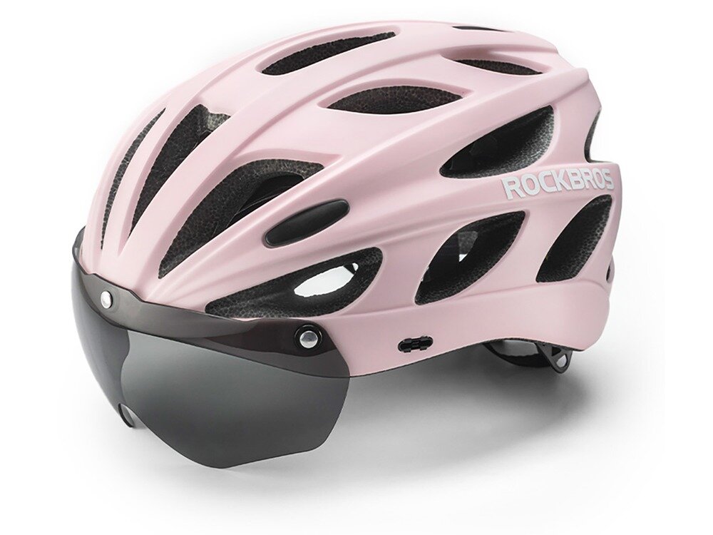 Różowy kask rowerowy z licznymi otworami wentylacyjnymi i przyciemnianą osłoną przeciwsłoneczną. Na boku widoczne jest logo \'ROCKBROS\'.