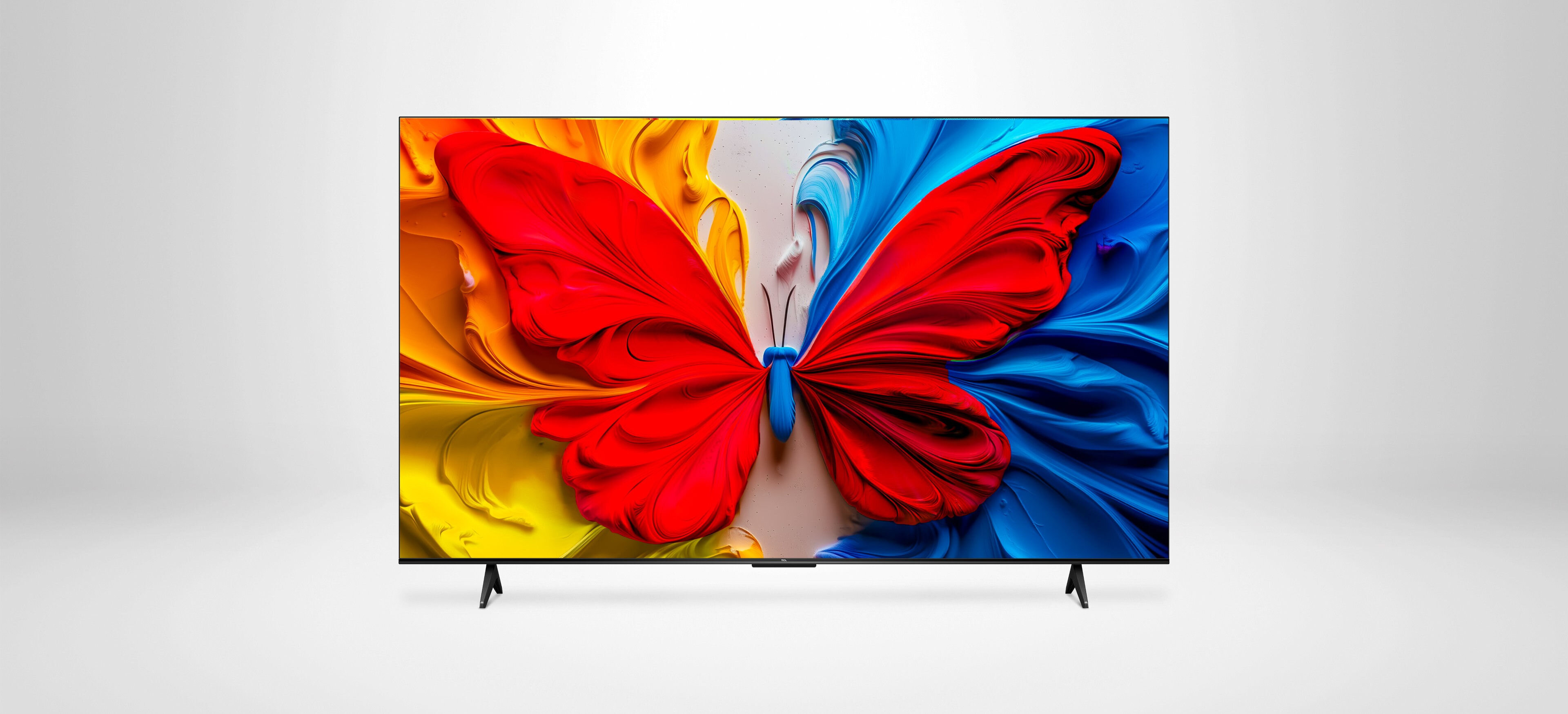 Telewizor TCL QLED z kolorowym motylem na ekranie w żywych barwach czerwieni, żółci i błękitu.