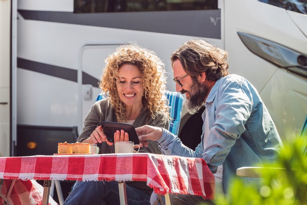 Nawigacja do kamerów TOMTOM GO Camper Max 700  2 ludzi korzysta z nawigacji przy stole    