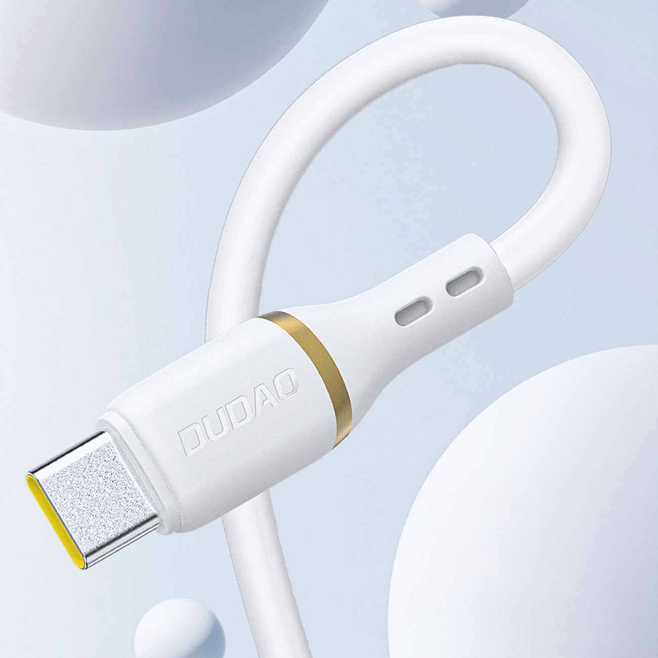 Biały kabel z końcówką USB-C, z widocznym logo \'DUDAO\' i złotym pierścieniem. Kabel jest w miękkim silikonowym oplocie, na tle jasnych, okrągłych kształtów.