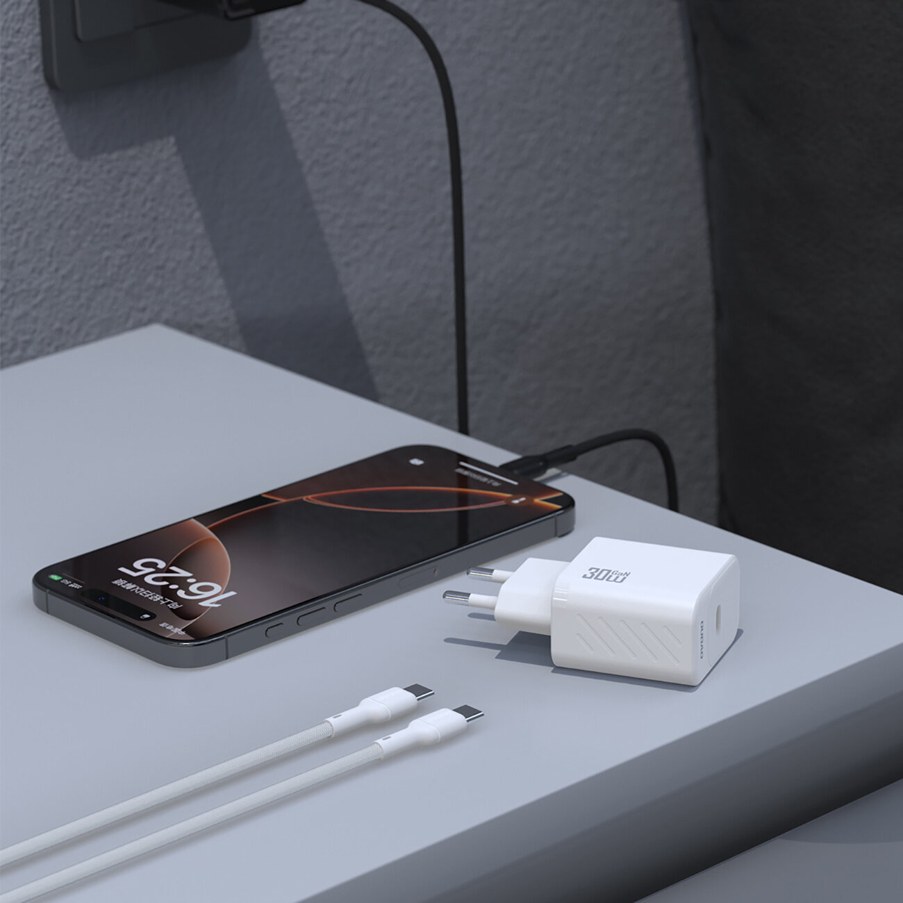 Na szarej powierzchni leży biały adapter z napisem \'30W\' oraz dwa białe kable USB-C. Obok znajduje się smartfon podłączony do ładowarki.