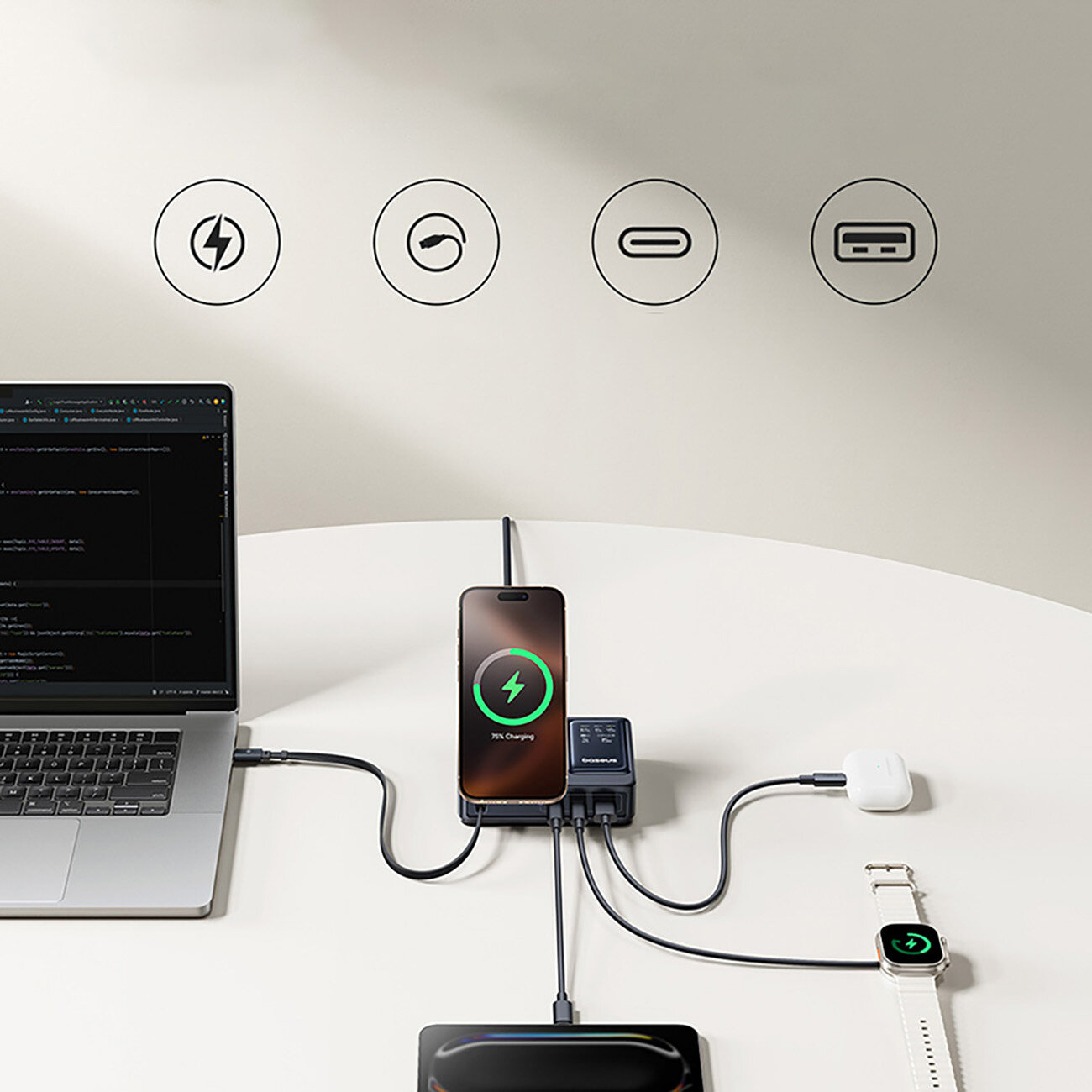 Na białym stole znajduje się laptop z podłączonym kablem, smartfon z ikoną ładowania, stacja ładująca z kilkoma kablami oraz smartwatch. Na ścianie widoczne są cztery ikony symbolizujące różne funkcje ładowania.