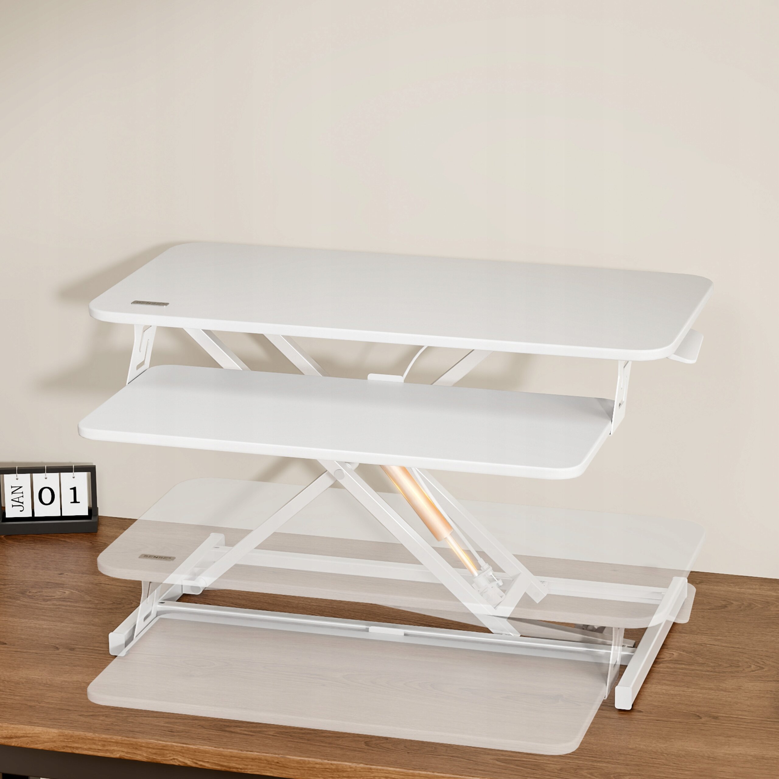 Białe biurko konwerter biurowy o wymiarach 81 x 40 cm z mechanizmem podnoszenia, ustawione na drewnianym blacie. Obok znajduje się kalendarz z datą \'JAN 01\'.