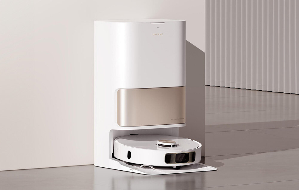 Na obrazie widoczny jest biały robot sprzątający z okrągłą stacją dokującą. Na stacji znajduje się logo \'DREAME\'.