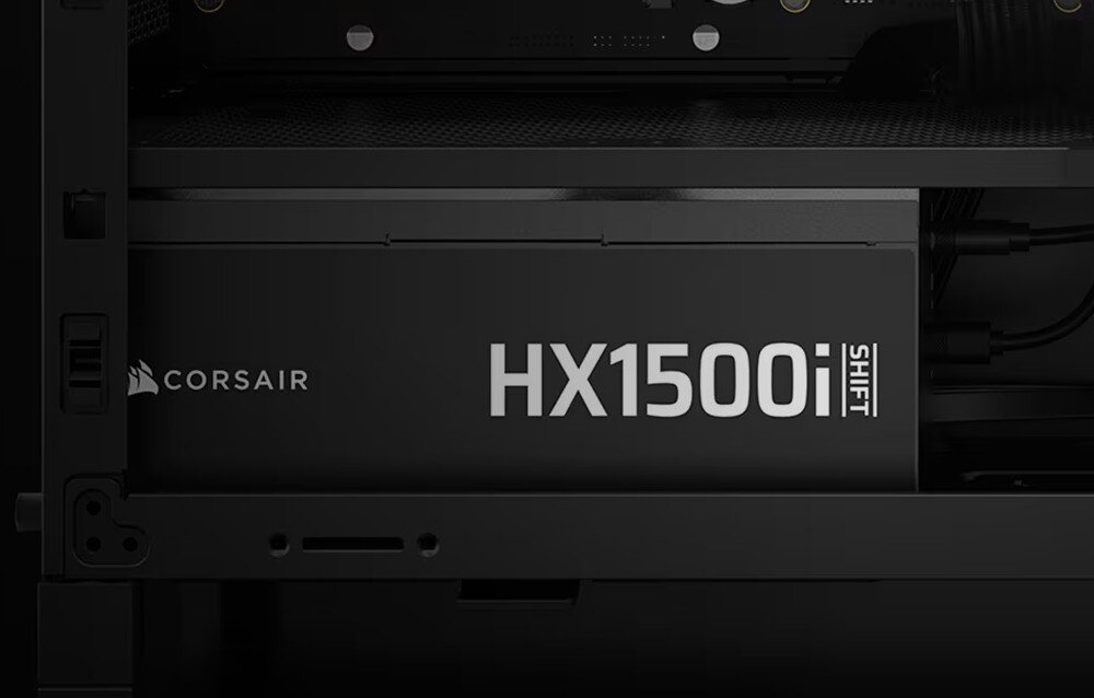 Obraz przedstawia wnętrze komputera z widocznym zasilaczem oznaczonym jako \'HX1500i SHIFT\'. Obok znajduje się logo \'CORSAIR\'.