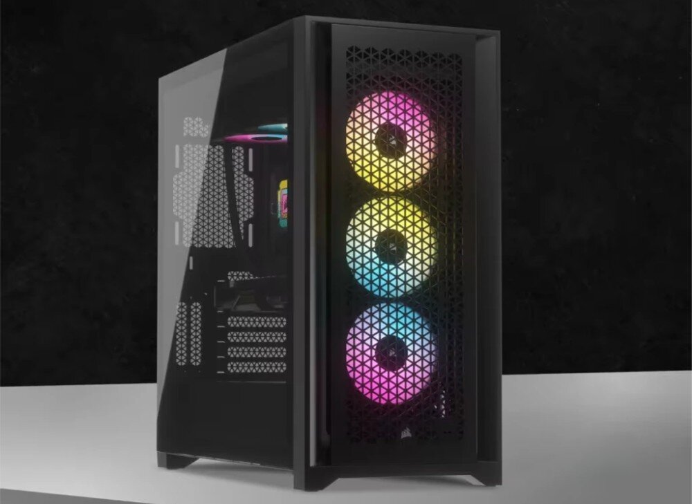 Obraz przedstawia komputer stacjonarny z przezroczystym panelem bocznym i trzema wentylatorami z podświetleniem RGB na przednim panelu. Obudowa ma czarny kolor i ażurowy wzór na przedniej części.