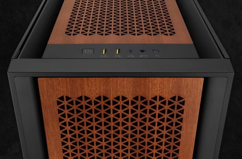 Obudowa komputera z drewnianymi panelami z geometrycznymi wycięciami. Na górze widoczne są porty USB, przycisk zasilania i inne złącza.
