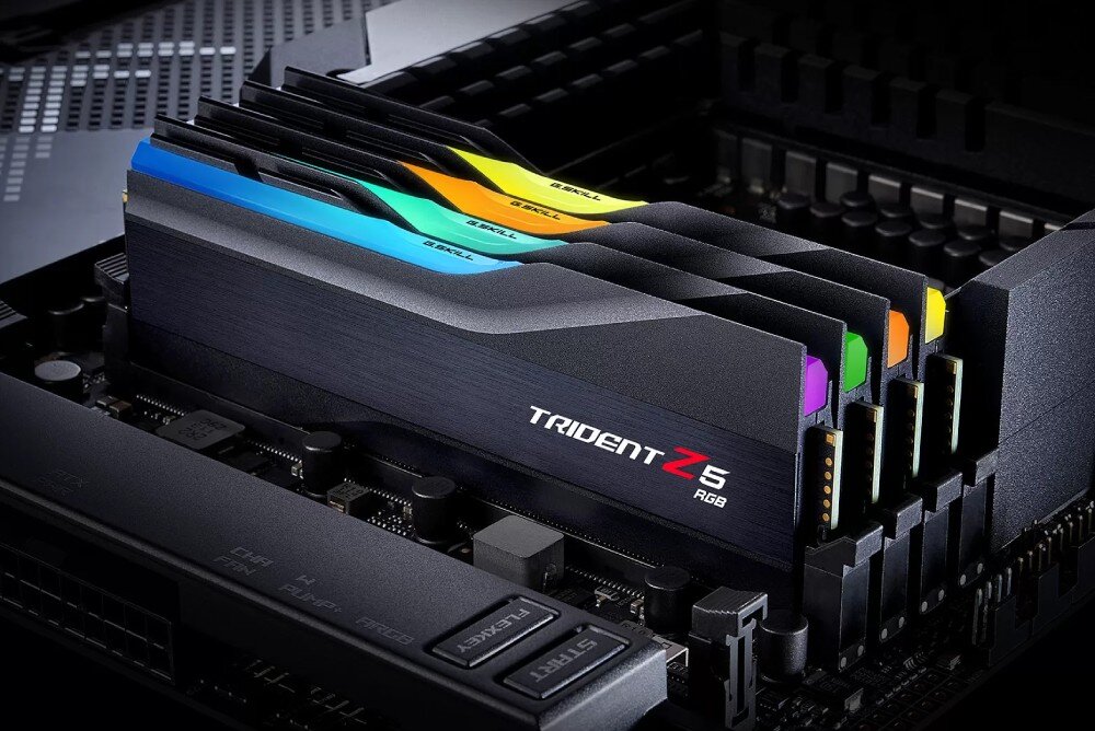 Na obrazie widoczne są moduły pamięci RAM z kolorowym podświetleniem RGB, umieszczone w gniazdach płyty głównej. Na jednym z modułów widnieje napis \'TRIDENT Z5 RGB\'.