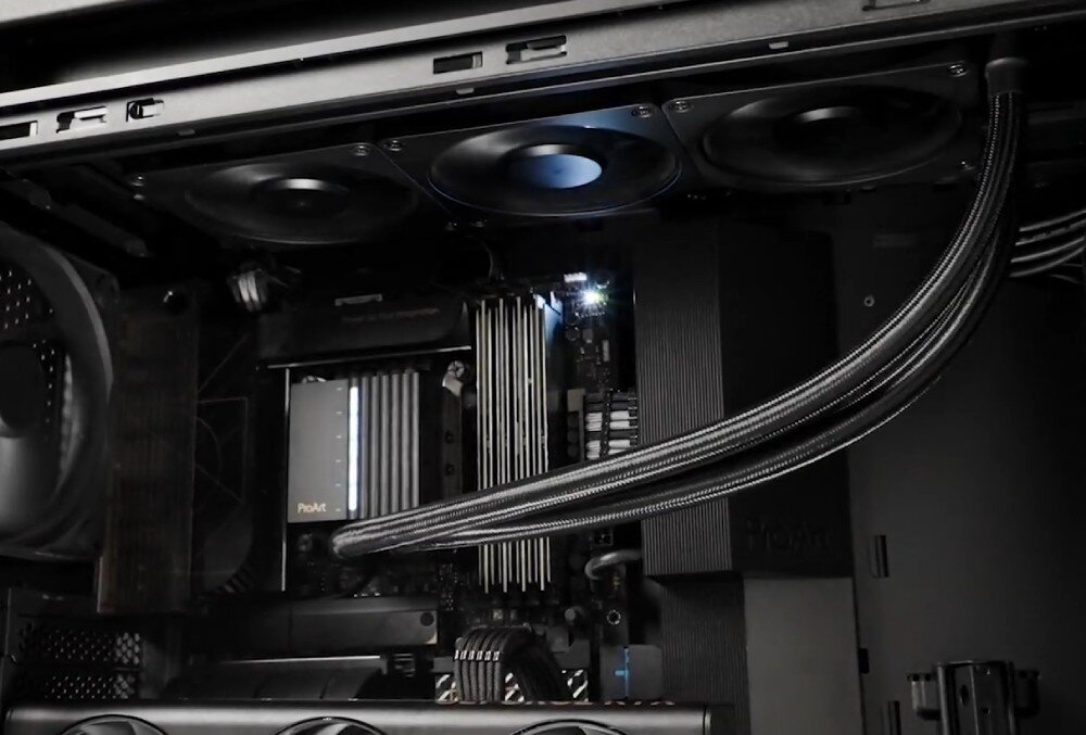 Wnętrze obudowy komputera z widocznymi elementami chłodzenia, kablami i podzespołami. Na jednym z elementów widoczny jest napis \'ProArt\'.